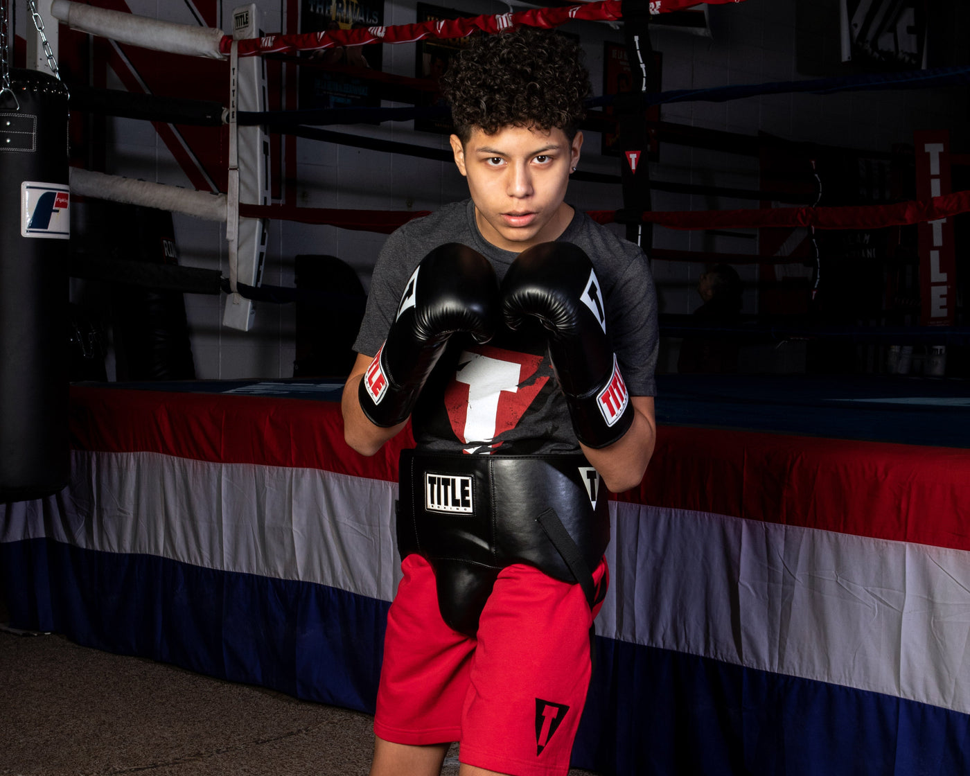 variant:black::TITLE Classic Super Bag Gloves 2.0 kid wearing protective cup and gloves
