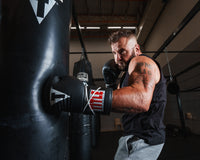 variant:lifestyle::TITLE Classic Boxing Sparring Bundle gloves on boxer hitting a bag
