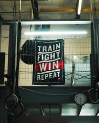 variant:lifestyle::TITLE Boxing Train Fight Win Repeat Banner on wall of boxing gym
