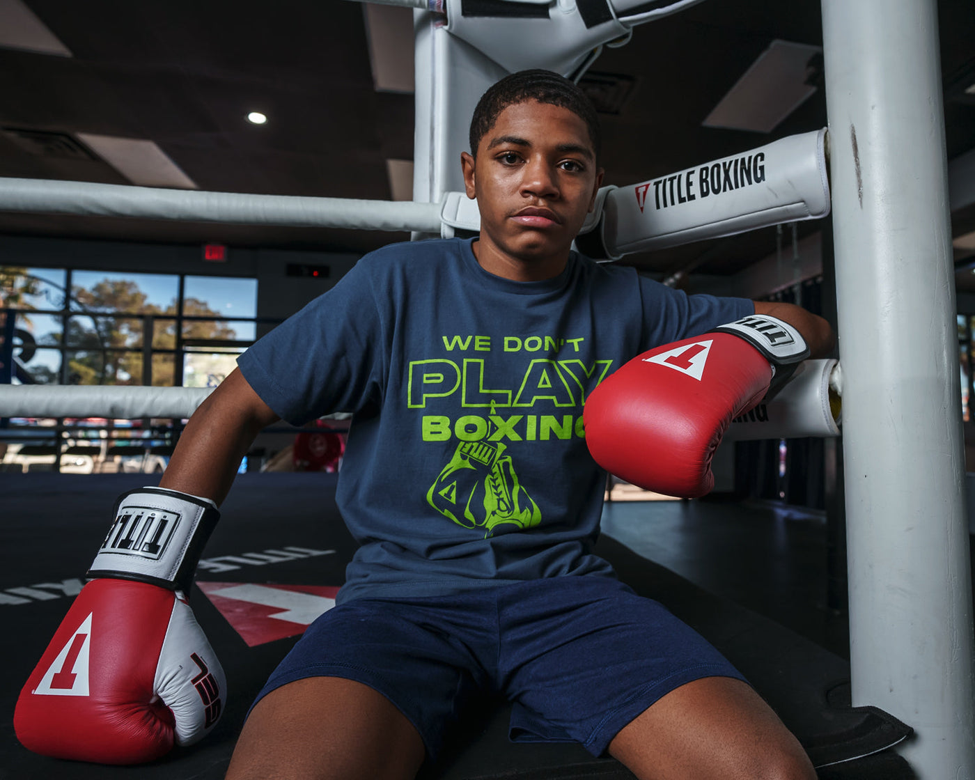 variant:red::TITLE Boxing Gel World Elastic Training Gloves kid sitting on ring