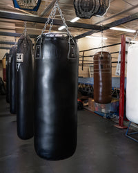 variant:black::TITLE Boxing KO-Vert Heavy Bag hanging in the gym