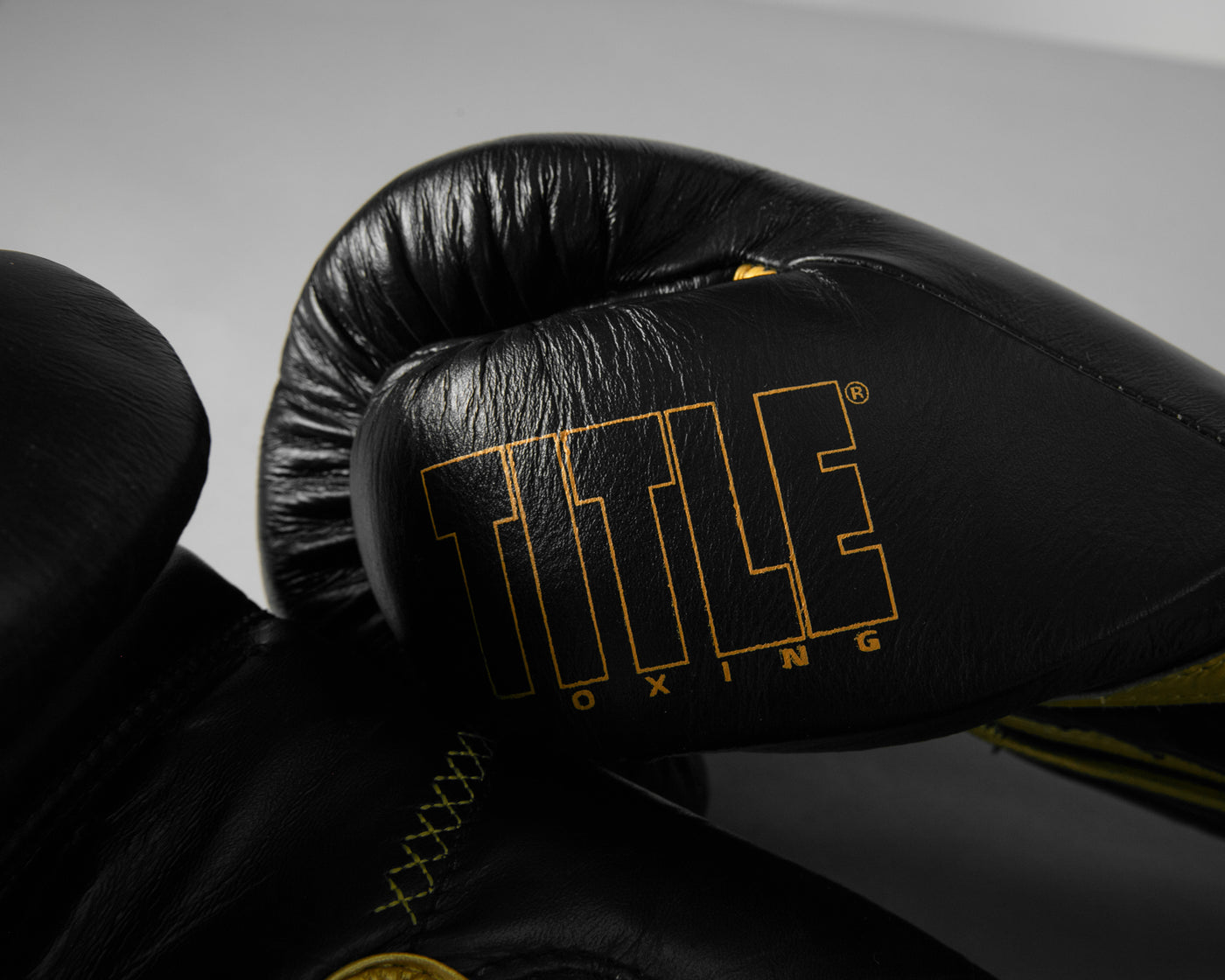 variant:black/gold::TITLE Boxing Momentum Pro Training Gloves closeup of logo on thumb