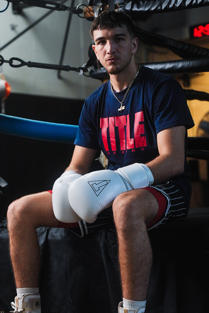 variant:white::TITLE Boxing Momentum Pro Training Gloves on boxer sitting on ring