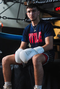 variant:white::TITLE Boxing Momentum Pro Training Gloves on boxer sitting on ring