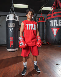 variant:Red/White::Pro Mex Professional Lace Sparring Gloves V3.0 kid standing between 3 bags