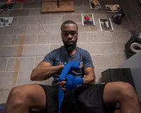 variant:royal::TITLE Boxing Select 180" Semi Elastic Mexican Hand Wraps guy sitting down putting on wraps