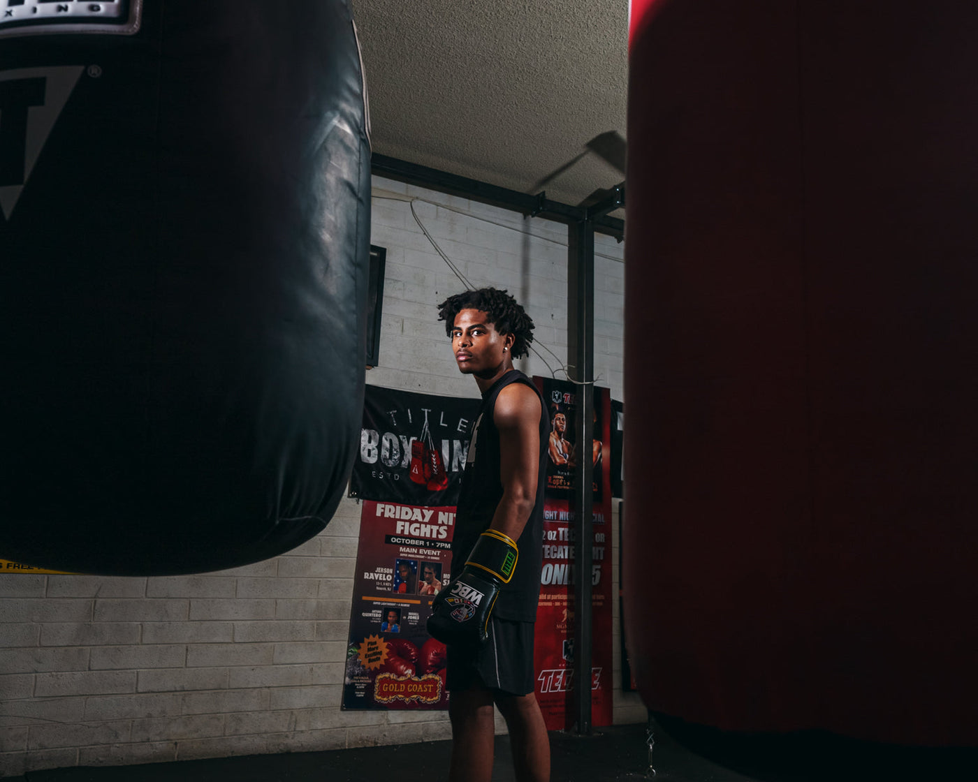 variant:Black/Green::WBC by TITLE Boxing Bag Gloves guy standing looking over shoulder by bag