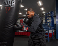 variant:lifestyle::TITLE Boxing Leather Big League Bag Gloves guy hitting a bag