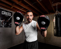 variant:lifestyle::TITLE Boxing Gel World Contoured Punch Mitts coach holding up mitts