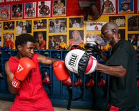 variant:lifestyle::TITLE Boxing Gel World Contoured Punch Mitts coach with boxer left hook