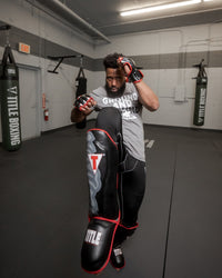 variant:lifestyle::TITLE Muay Thai Pao Shin-Instep Guards 2.0 man blocking with his leg