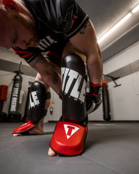 variant:lifestyle::TITLE Boxing Pro Style Shin & Instep Guards 3.0 guy putting on shin guards